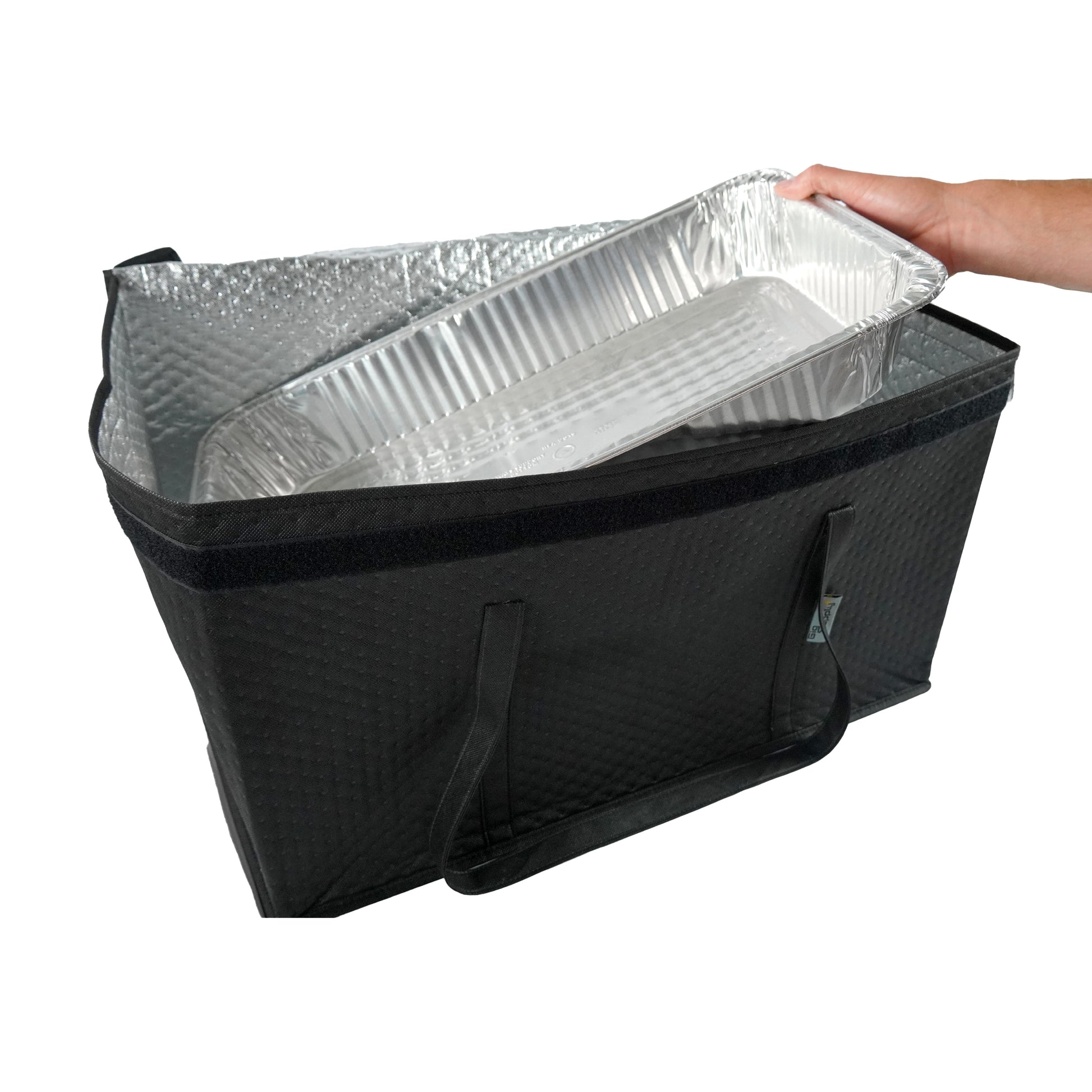 Black insulated food delivery bag with aluminum pans inside, held by a hand on a white background